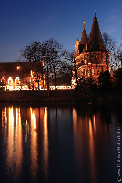 Lübecker Holstentor Nachtfoto Weihnachtslichter Spiegelung in Wasser der Trave